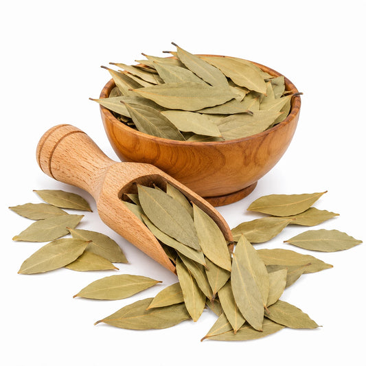 Wooden bowl and scoop filled with bay leaves on a white background