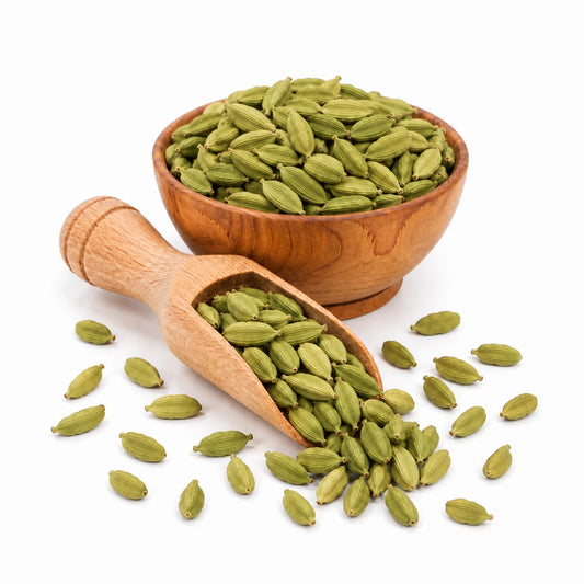 Green cardamom pods in a wooden bowl and scoop on a white background