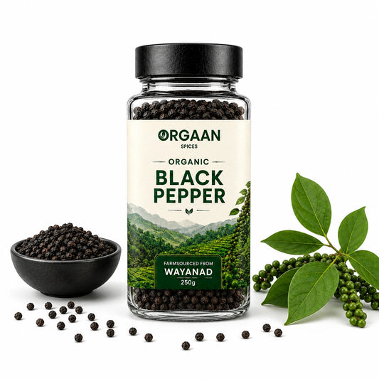 Jar of Orgaan organic black pepper with black pepper in a bowl and green leaves on a white background