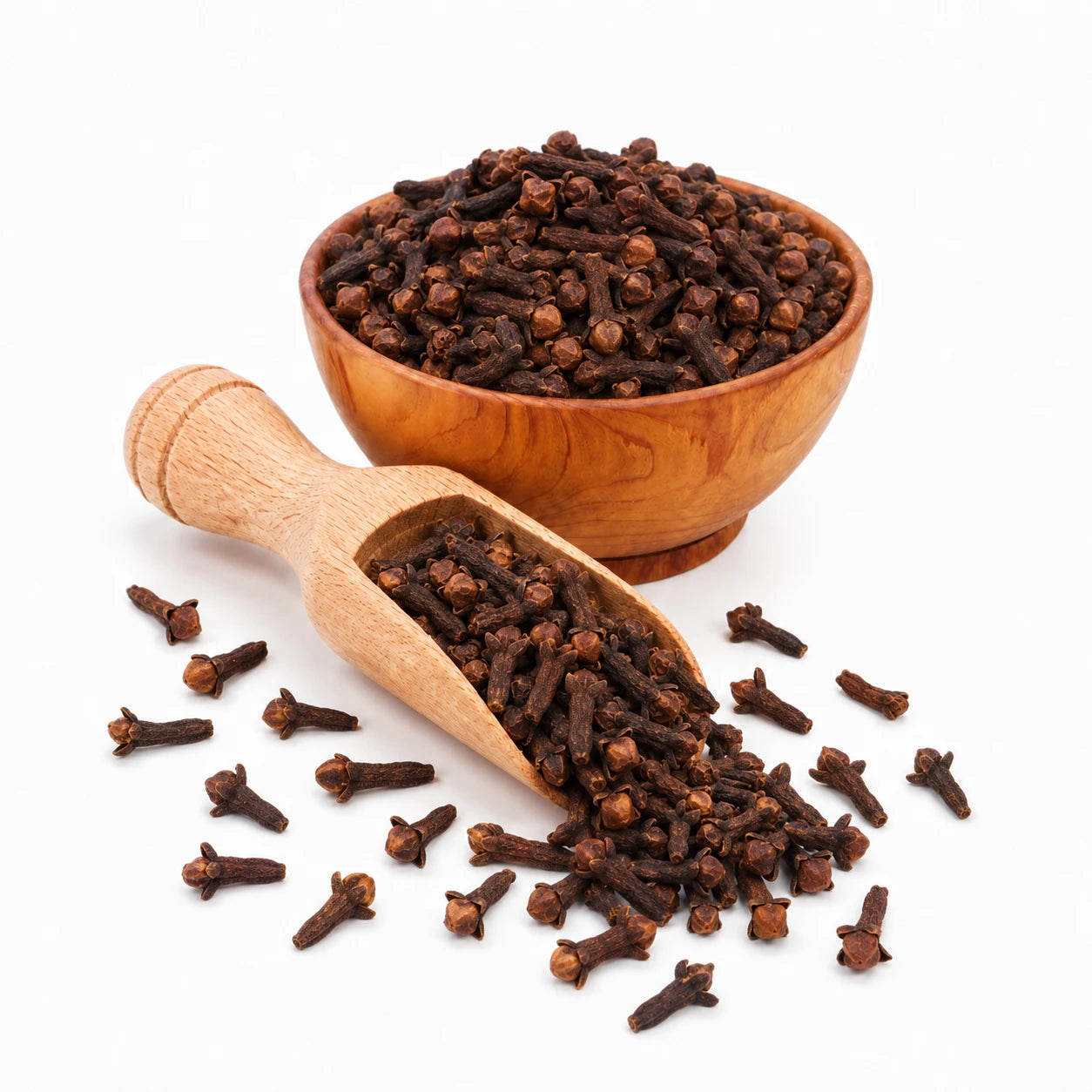 Wooden bowl and scoop filled with cloves on a white background