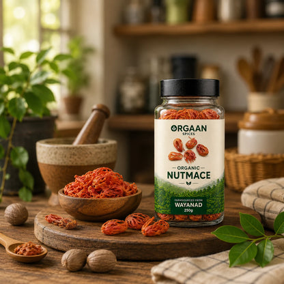 Jar of Orgaan Organic Nutmace on a wooden table with nuts and a mortar and pestle in the background.